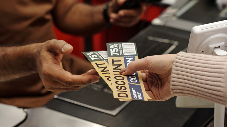 Customer handing cashier coupons at store
