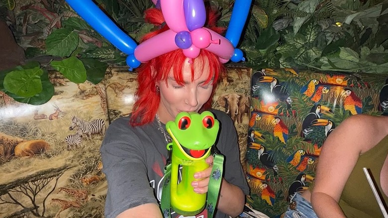 Person celebrating at Rainforest Cafe with balloon hat and drink