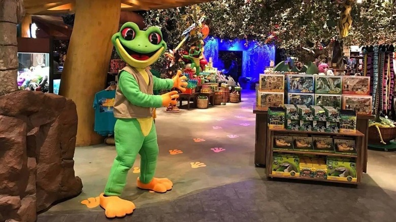 Mascot dressed in a frog suit gesturing inside Rainforest Cafe