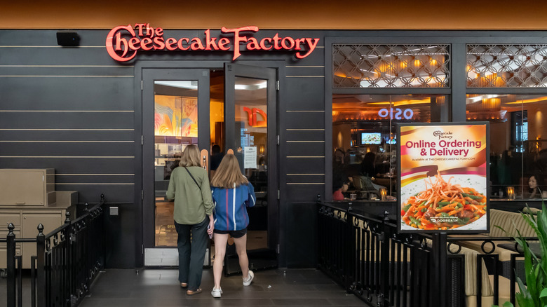 Two people walking into The Cheesecake Factory