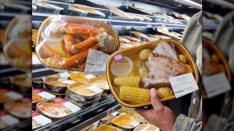 A man holding two Gold Pan meals from Wegmans with lobster and crab legs