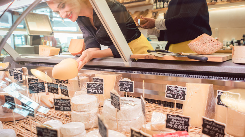 An employee sorts cheese in the cheese case at the grocery store