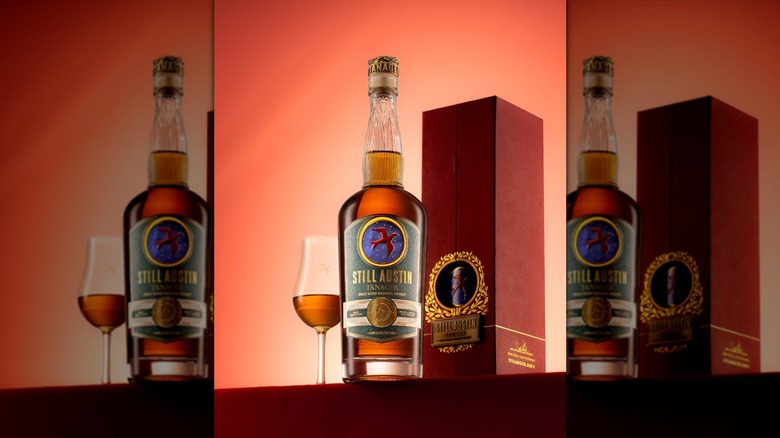 Mirrored image of Still Austin bourbon with tulip glass and box