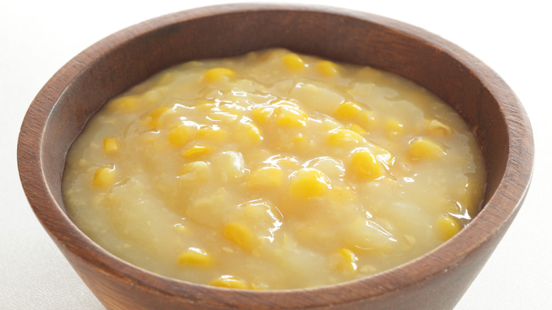 Creamed corn in a wood bowl on white background