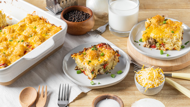 Slices of sausage and cheese breakfast casserole served on two plates with the casserole on the left