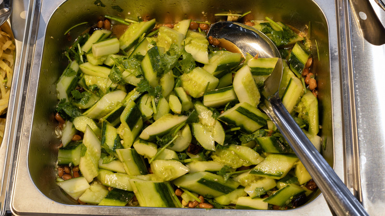 Cucumber salad with whole peanuts and serving spoon