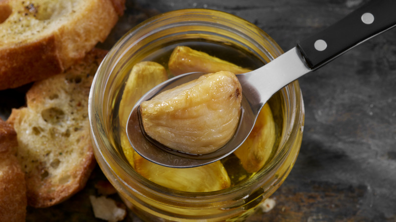 Garlic coffee on a spoon being held above a jar with bread off to the side
