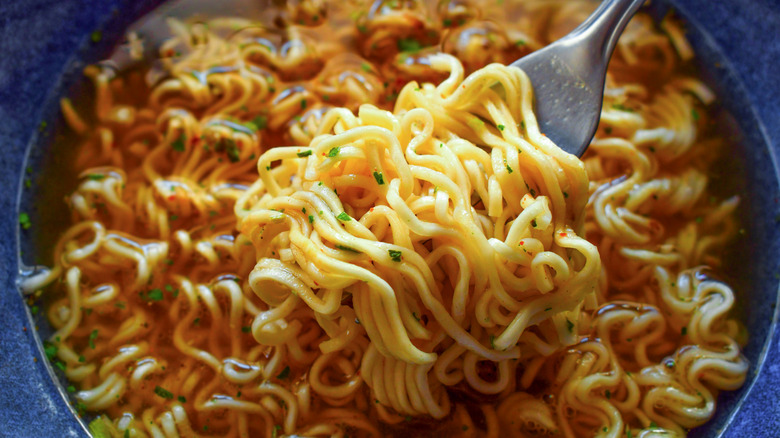 a closeup photo of a forkful of instant ramen being scooped out of a bowl