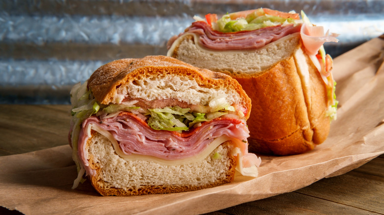 Italian sandwich cut in half, filled with cheese, deli meats, lettuce, and onions