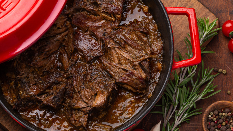 Top view of beef pot roast with herbs and spices on the side