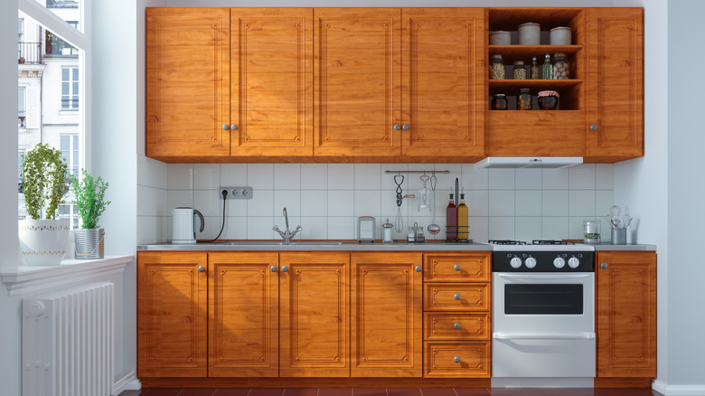 Kitchen with retro wooden cabinets against white tiles and walls