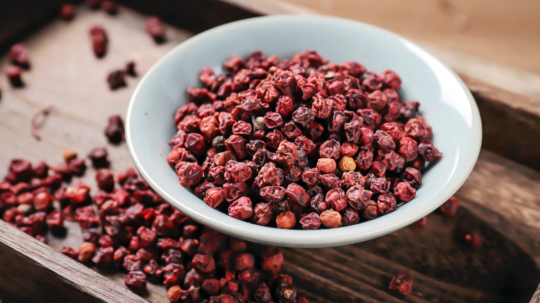 Bowl of Sichuan peppercorns on a wooden tray