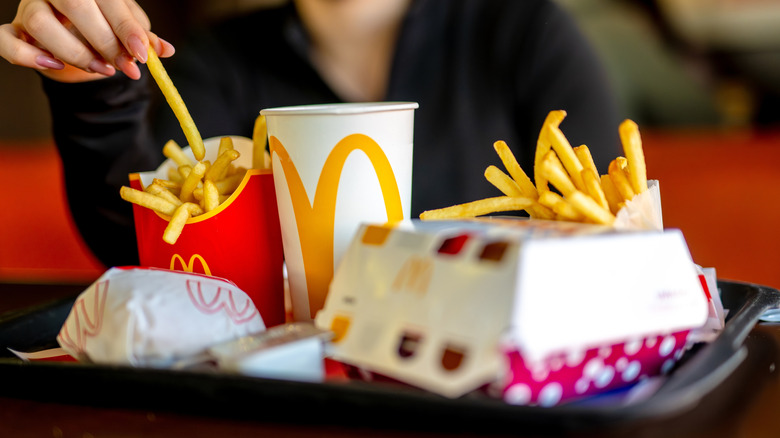 Person holds french fry above tray of McDonald's food