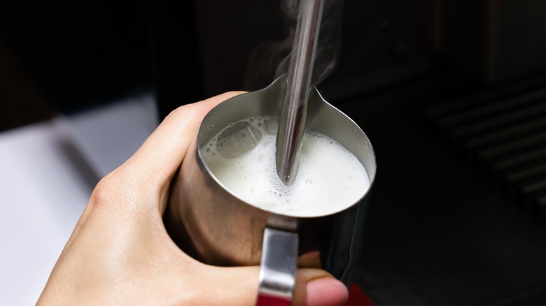 barista frothing milk with steamer wand 