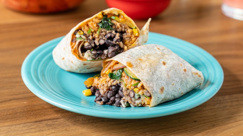Burrito with black beans cut in half on a plate