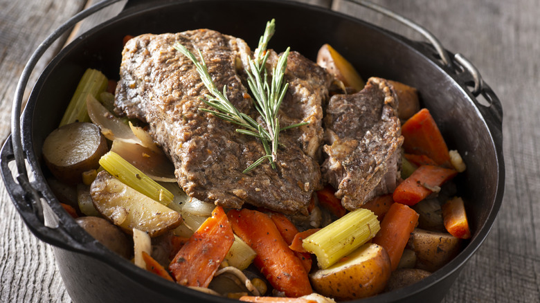 traditional pot roast with carrots and potatoes in dutch oven
