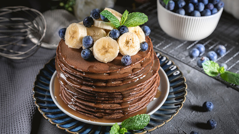 A stack of brownie mix pancakes topped with blueberries and bananas