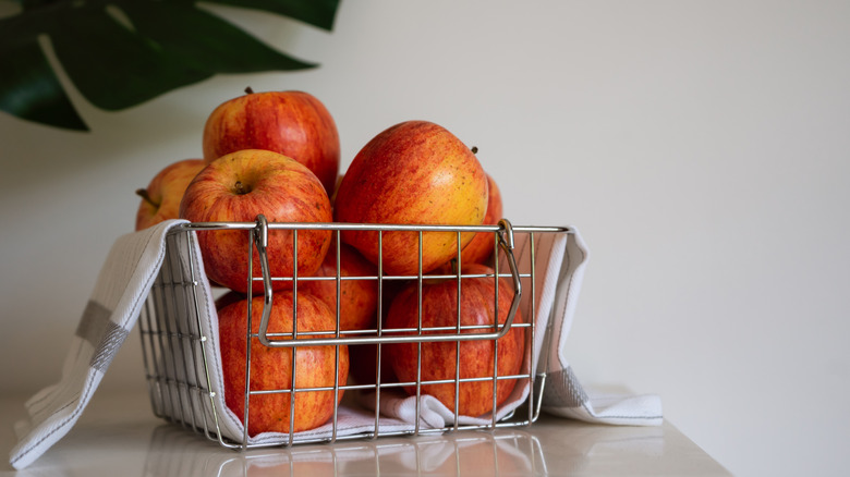 Red apples in silver wire basket lined with white towel