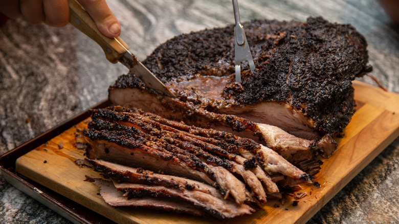 A person slicing a barbecue beef brisket