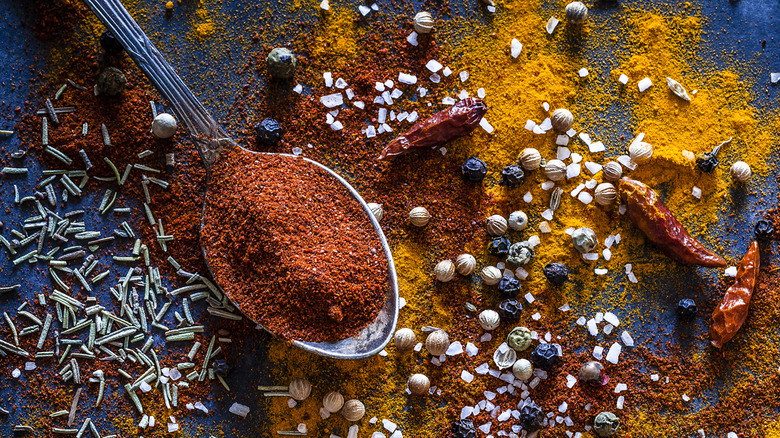 Spoonful of mixed seasonings and spices spilled on a table.