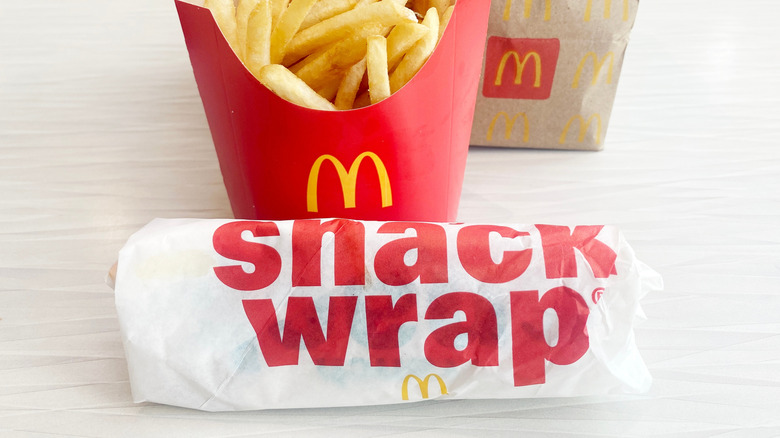 McDonald's Snack Wrap wrapped in white paper in front of red cardboard box of French fries