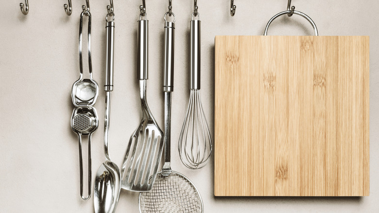 Hanging utensils and cutting board on a white wall