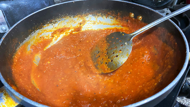 tomato sauce reducing in a saucepan