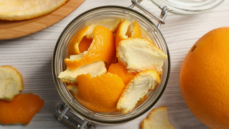 A glass jar is filled with pieces of orange peel.