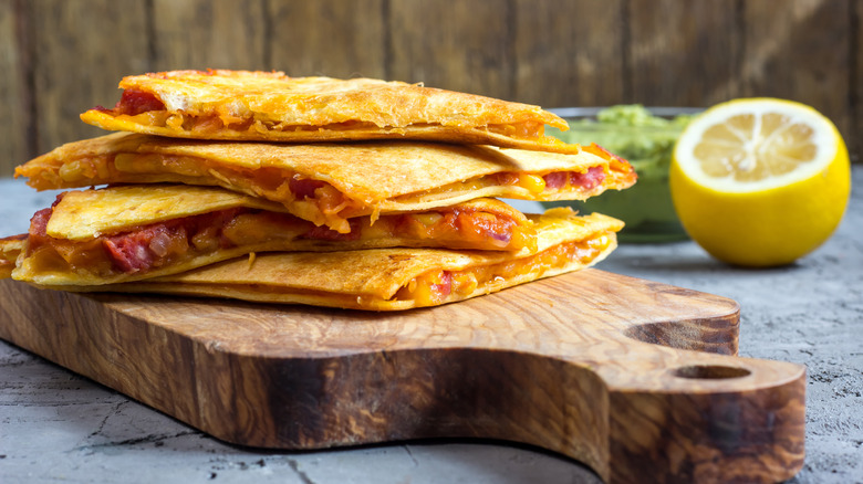quesadilla with cheese and sausage sliced on a cutting board with lemon in background