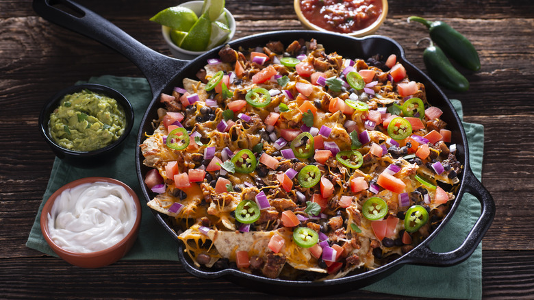 shredded chicken nachos in skillet with toppings