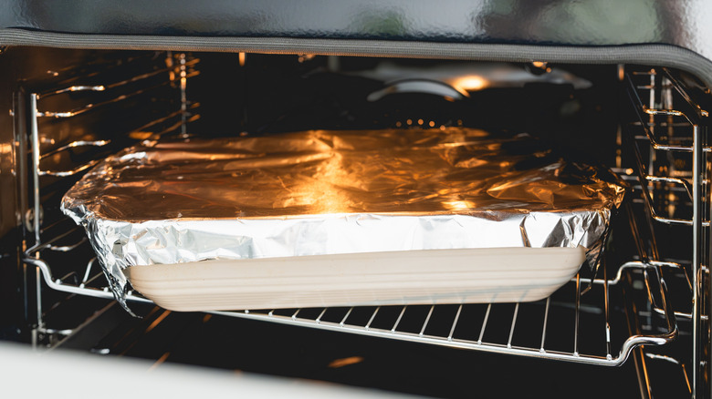 Foil-covered baking dish in oven