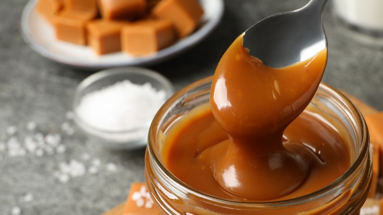 caramel sauce with spoon in glass jar