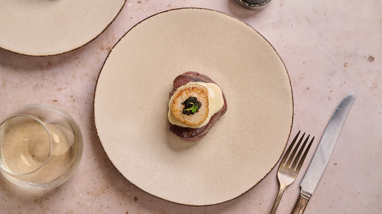 steak and scallop stacked on a plate