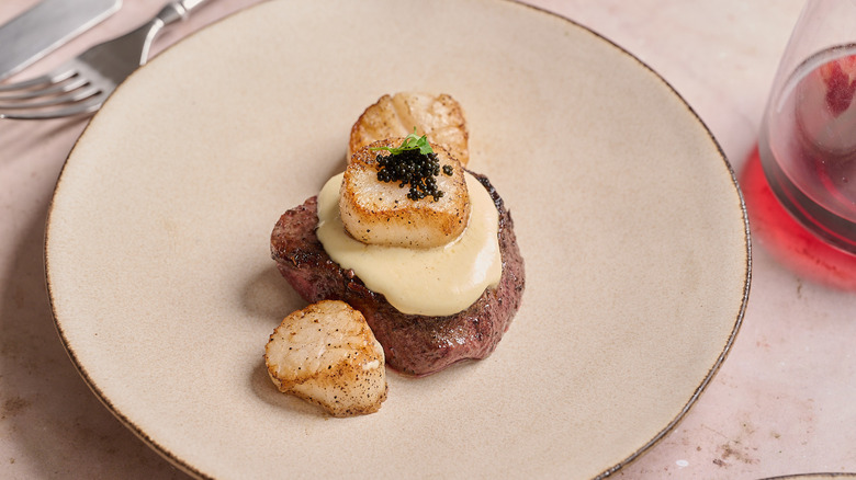 steak and scallops on a plate with sauce