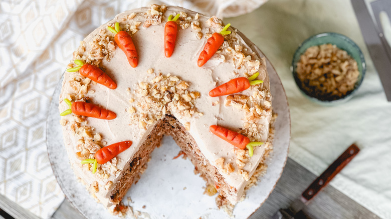 Vegan carrot cake with cinnamon-cashew frosting with one piece cut out on serving platter
