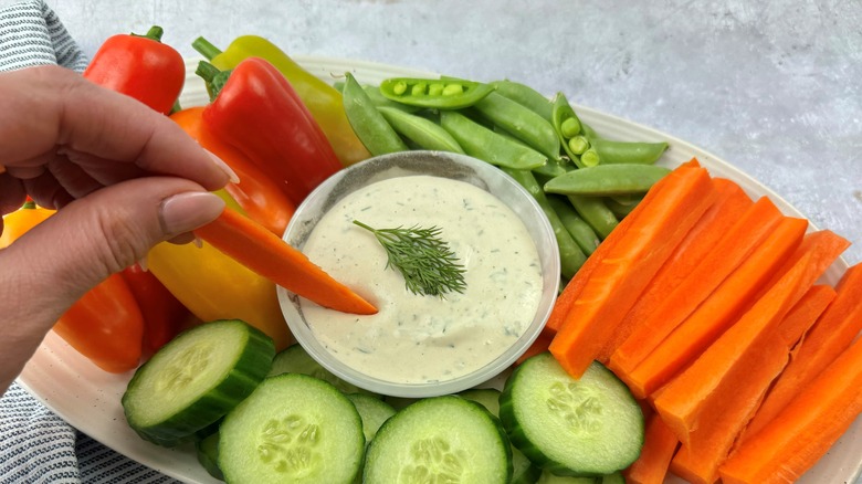 hand sticking carrot in ranch dip