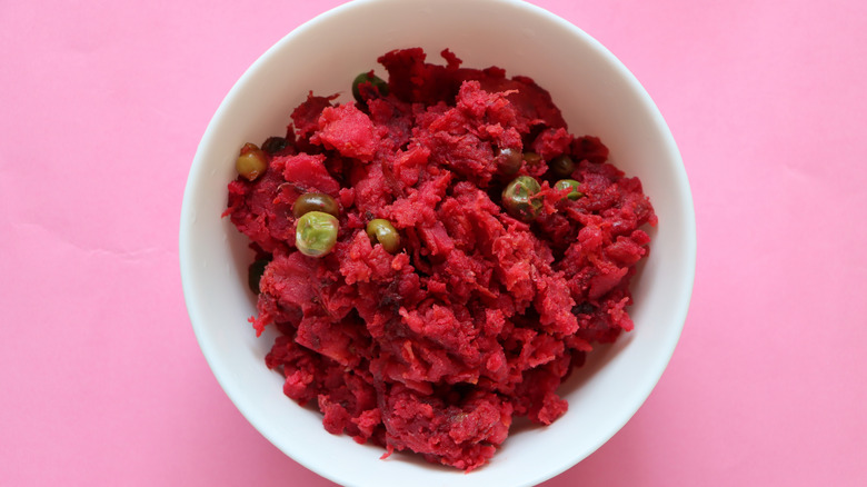 Beets mashed with potatoes in a bowl with a pink background