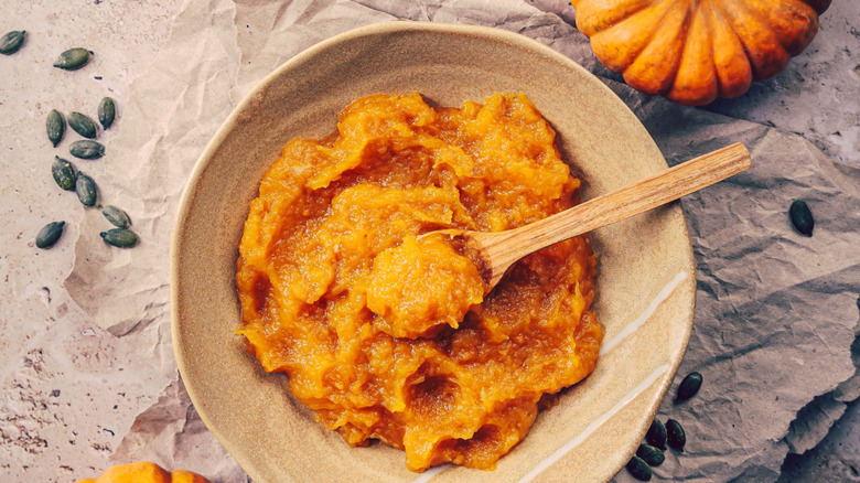 Mashed pumpkin puree with small pumpkins in the background