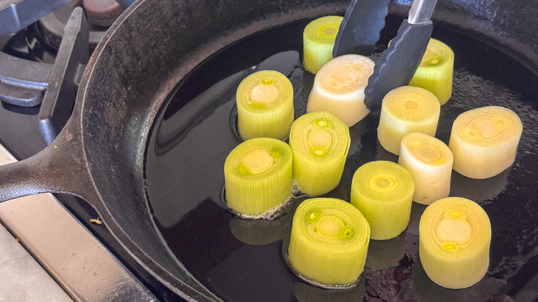 tongs adding leek to pan