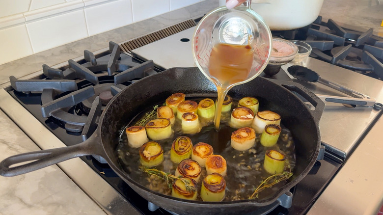 adding broth to pan with leeks