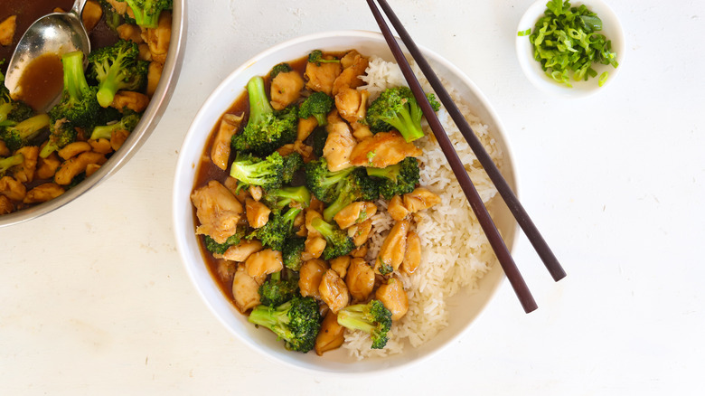 chicken and broccoli in a bowl with rice and chopsticks