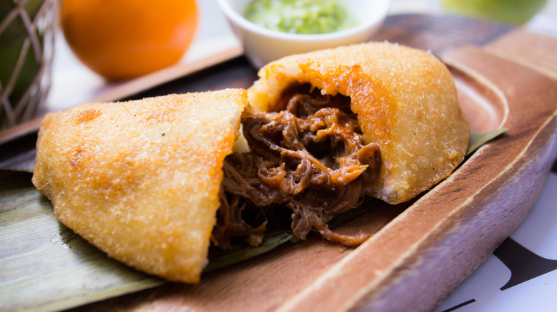 Venezuelan cornmeal empanada pulled apart to reveal a shredded beef filling