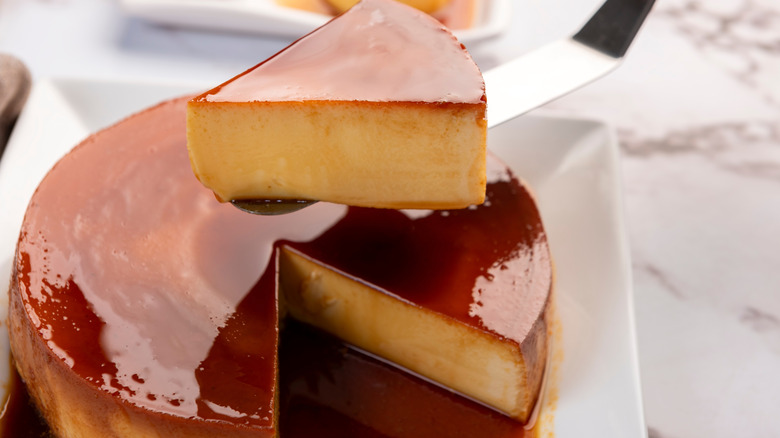 Spatula holding a slice of quesillo flan over the entire dessert