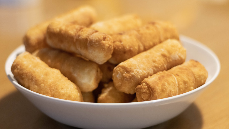 Pile of crispy tequeños in a white bowl