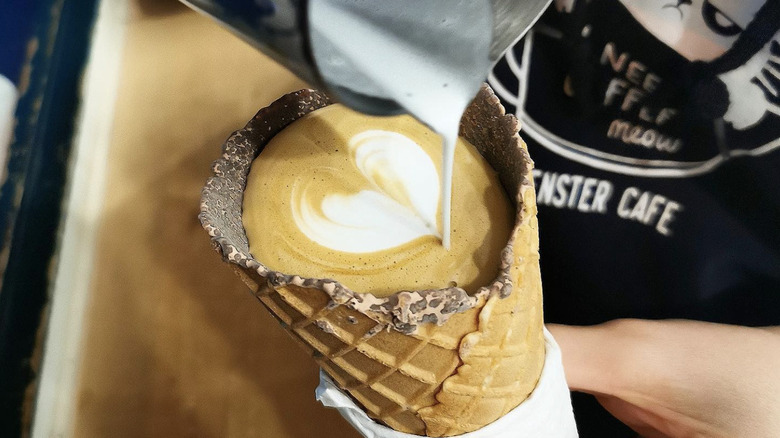 barista pouring latte into cone
