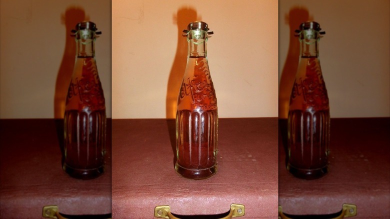 Mirrored image of glass afri-cola bottle on a suitcase