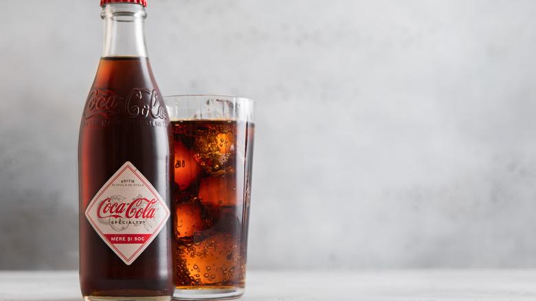 Glass bottle of vintage Coca Cola and some poured into a drinking glass