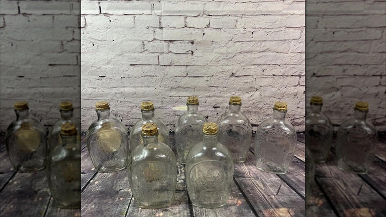 set of vintage maple syrup bottles on wooden boards against wall