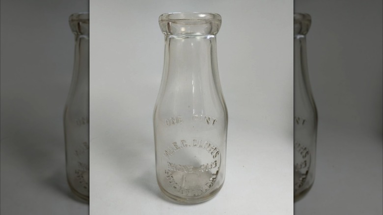 mirrored image of empty glass milk bottle against grey background