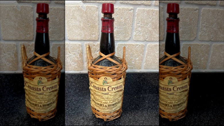 Canasta Cream sherry bottle in basket against wall mirrored image